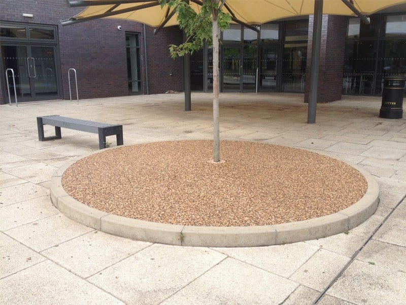 Circular resin bound tree pit with a raised kerb in a paved square