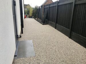 Resin bound side path beside a dark timber fence
