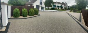 Grey resin bound driveway sweeping past a hedge
