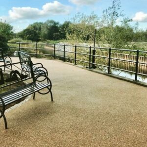 Resin bound terrace with a metal bench and railings by a lake