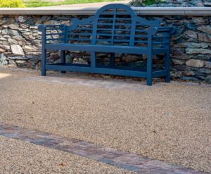 Resin bound area with a blue garden bench against a stone wall