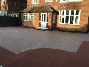 Two-tone red and silver resin bound driveway at a brick house